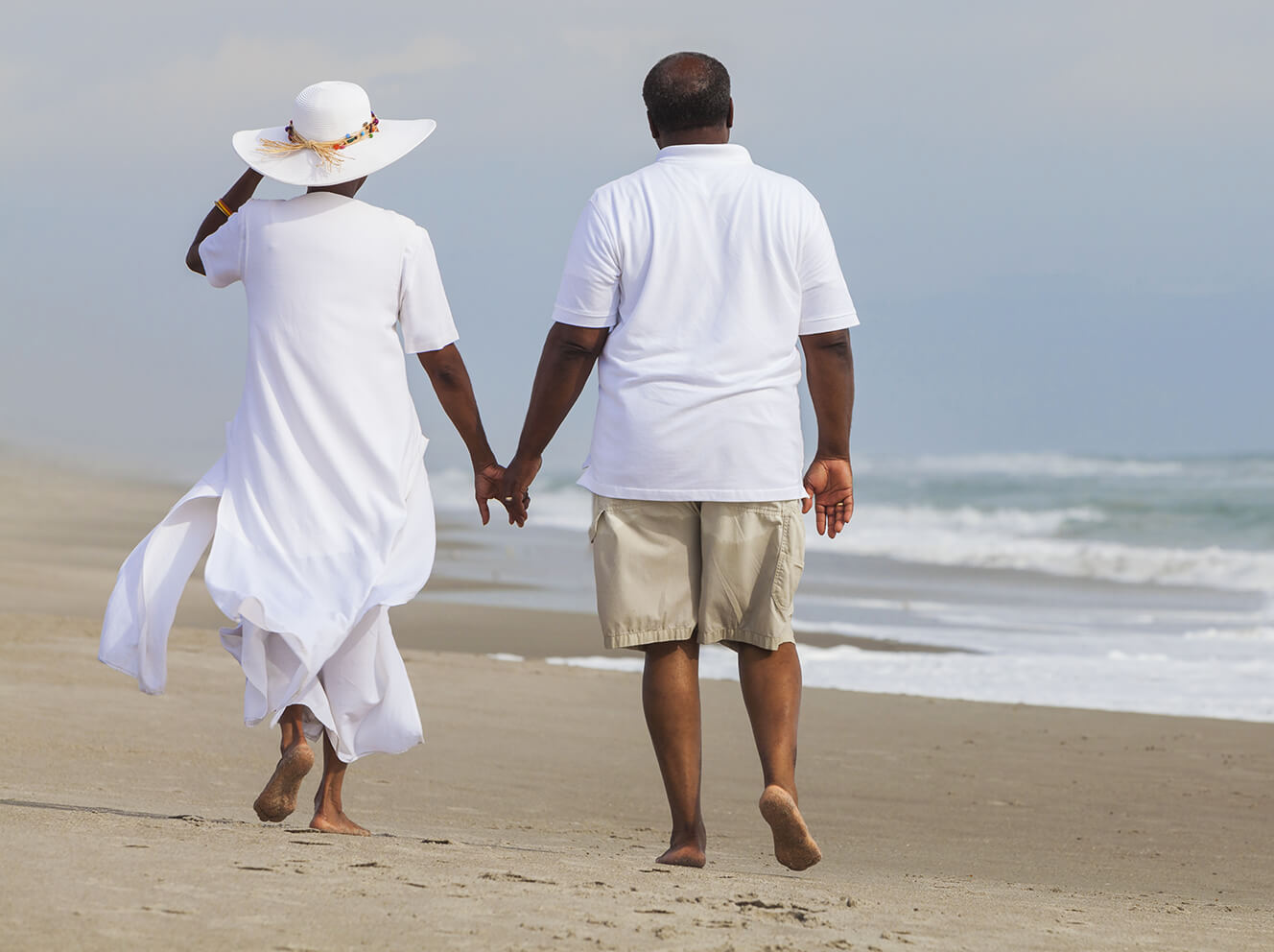 African American couple holding hands while walking on the beach