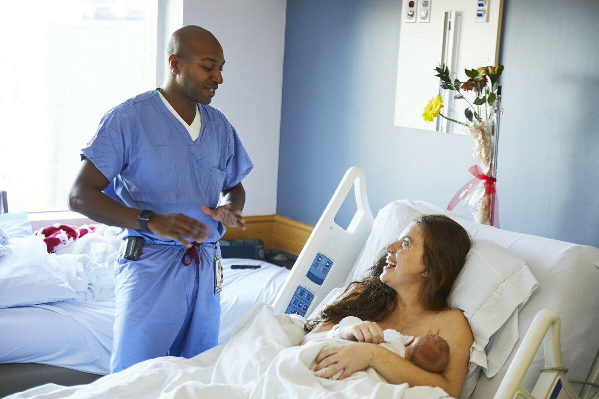 Healthcare worker talks to new mother with baby.