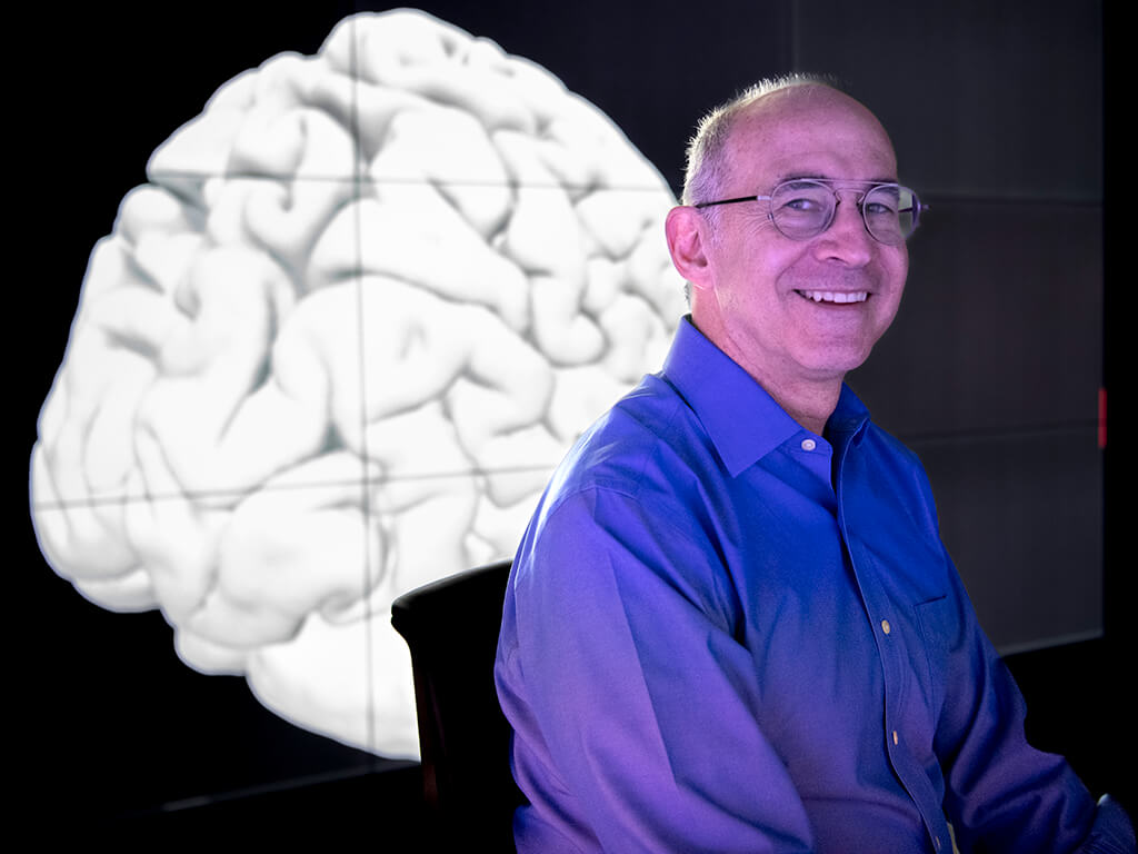 Man sitting in front of digital image of brain