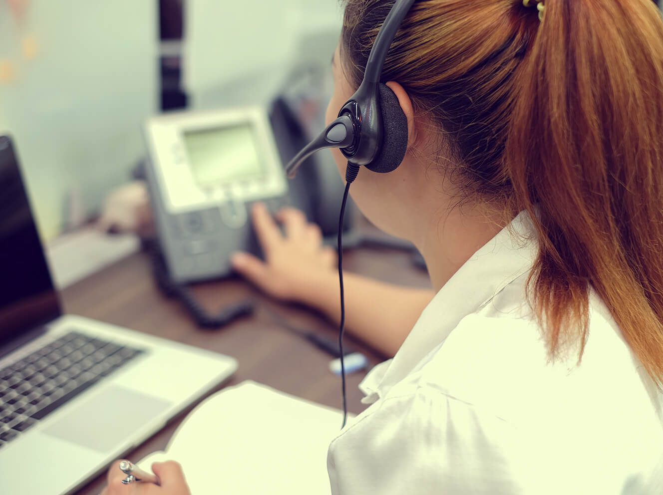 Woman making phonecall with headset on and at computer
